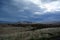 Lava field in Iceland in West fjords area on the background of distant mountains and stormy sky .