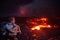 Lava flow man hiker on night hike watching magma erupting flowing from volcanic eruption in Kilauea volcano, Big Island