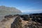 Lava rock beach on Mokolii Island [also known as Chinamans Hat] looking toward Kualoa mountains on the North Shore of Oahu Hawaii