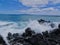 Lava Rock and Coral with Spray of crashing wave in tide pools at Maluaka Beach and Kihei Maui with sky and clouds