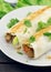 Lavash rolls with meat, vegetables and cheese served with green