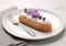 Lavender cream eclair on plate in fine dining restaurant.Macro.AI Generative