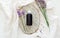 Lavender flowers with lavender essential oil bottle on white wooden rustic board and fabric. Aromatherapy treatment, natural