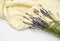 Lavender flowers and stems on an unfolded beige towel and a white background.
