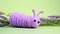 Lavender Knitted Caterpillar Toy On A Bed Of Purple Flowers