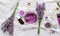 Lavender oils, liquids, parfumes, lavender flowers on white fabric. Set skincare spa beauty cosmetic products. Lavender essential