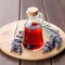 Lavender syrup on a wooden tray with flowers and a small spoon.