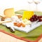 Lavish marble serving tray with cheese, crackers, grapes, apricots, bread sticks,and cheese knives.