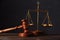 Law and justice concept. Lawyers desk. Judge`s gavel, scales, wooden table. Dark gray bokeh background