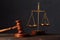 Law and justice concept. Lawyers desk. Judge`s gavel, scales, wooden table. Dark gray bokeh background