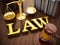 Law word, gavel and balanced scale on wooden table. 3D illustration