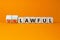 Lawful or unlawful symbol. Turned wooden cubes and changed the word unlawful to lawful. Beautiful orange table, orange background