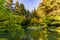 Lawn with clipped green grass near the river with a reflection o