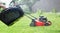 Lawn grass mowing. Washing the lawn mower\'s grass catcher with water. Splashes of water on a background of green grass.