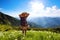 On the lawn in mountains landscapes the hipster girl in dress, stockings and straw hat.