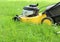 Lawn mover cutting high grass in garden