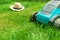 Lawn mower mowing green grass and a sunhat.  work in the garden.