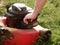 Lawn mowing. A man fills up a lawn mower with gasoline. Refilling the fuel tank in a petrol lawn mower