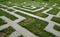 Lawn in the park with gray tiles arranged in the shape of a large maze which is for children. You can`t get lost in it and finding