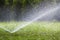 Lawn water sprinkler spraying water over grass in garden on a hot summer day. Automatic watering lawns. Gardening and environment
