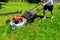 Lawnmower being used by gardener for mowing grass