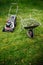 Lawnmower and wheelbarrow with grass on mown lawn