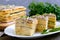 Layer cake with eggs, cheese, green onions, canned fish, mayonnaise on a white plate on a wooden table. Festive appetizer. Close-