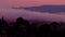 A layer of fog settles over silhouetted hills of Sausalito as sunset turns night