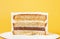 Layered cake with soft caramel, lemon curt and cream cheese frosting on the yellow background