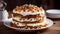 A layered carrot cake with cream cheese frosting and chopped nuts on top