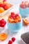 Layered chia seeds pudding with apricot, raspberry in glasses on white wooden background. Mousse with chia seeds