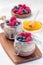 Layered chocolate and peanut butter chia seed pudding in jar, garnished with raspberry and blueberry, vertical