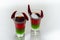 Layered drink shot prepared with vodka, green liquor, grenadine and lemon juice decorated with bird eye chillies in the shape of