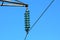 Layered high quality tall glass power line utility insulators holding single black electrical wire on strong metal utility pole