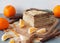 Layered honey cake with chocolate cream, pieces of fruit on a gray background with oranges. Food background