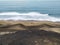 Layered landscape of different shades of sand and blue sea. Volcanic black sand after low tide. View from above of a scene on the