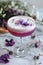 Layered purple cocktail with floral decoration in glass on wooden tray