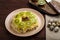 Layered salad with chicken and kiwi next to the board kiwi and quail eggs and a knife on a napkin.