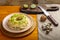 Layered salad with chicken and kiwi with nuts next to quail eggs on a kiwi napkin on a board and a knife on the table.