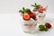 Layered strawberries dessert with cream cheese on white background
