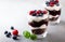 Layered trifle dessert with chocolate sponge cake, whipped cream, berries and fruit jelly in serving glasses