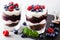 Layered trifle dessert with chocolate sponge cake, whipped cream, berries and fruit jelly in serving glasses