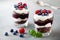 Layered trifle dessert with chocolate sponge cake, whipped cream, berries and fruit jelly in serving glasses