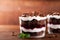 Layered trifle dessert with chocolate sponge cake, whipped cream and fruit jelly in serving glasses