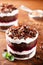 Layered trifle dessert with chocolate sponge cake, whipped cream and fruit jelly in serving glasses