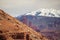 A layered Utah landscape showing a hillside, sandstone pinnacles, rocky cliffs and snowy mountains.