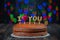 Layers of a cake with I love you candles, a heart placed on a vintage table and colorful bokeh patterns in the