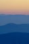 Layers of silhouettes of hills in colors of twilight and orange sky after sunset