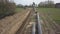 Laying gas pipeline among green hills. Large high-pressure steel pipes prepared for immersion in the excavated trench. Land works