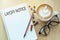 Layoff notice word on notebook with glasses, pencil and coffee cup on wooden table. Business concept